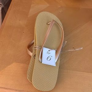 Golden tannish colored flip flops in a size 6